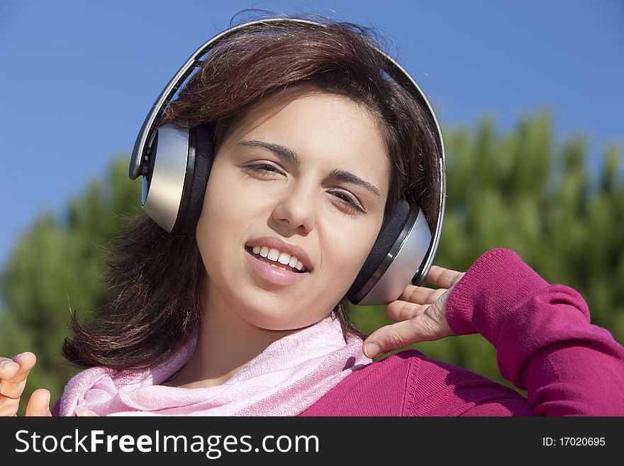 Pretty young girl listening music in the park