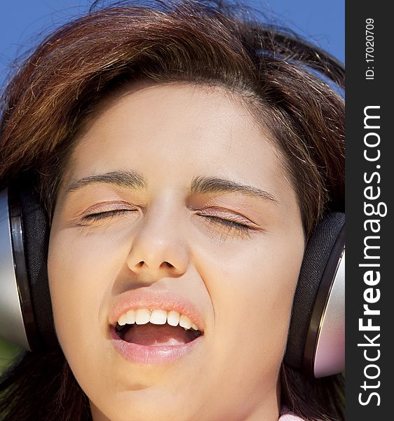 Pretty young girl listening music in the park