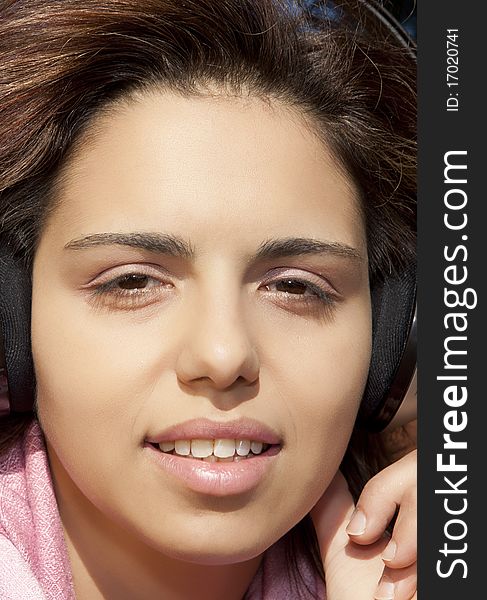 Pretty young girl listening music in the park