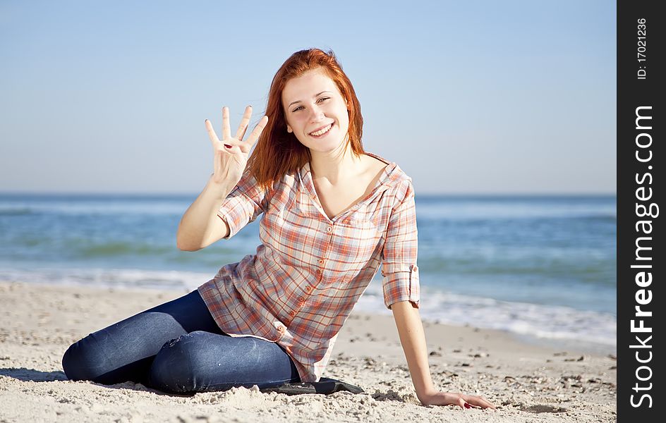 Happy red-haired girl at the beach. Outdoor shot.