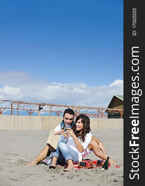 Happy young couple enjoying picnic on the beach and have good time on summer vacations. Happy young couple enjoying picnic on the beach and have good time on summer vacations