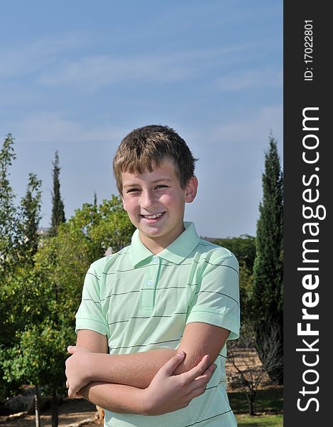 Portrait of a boy in a city park against the trees and blue sky