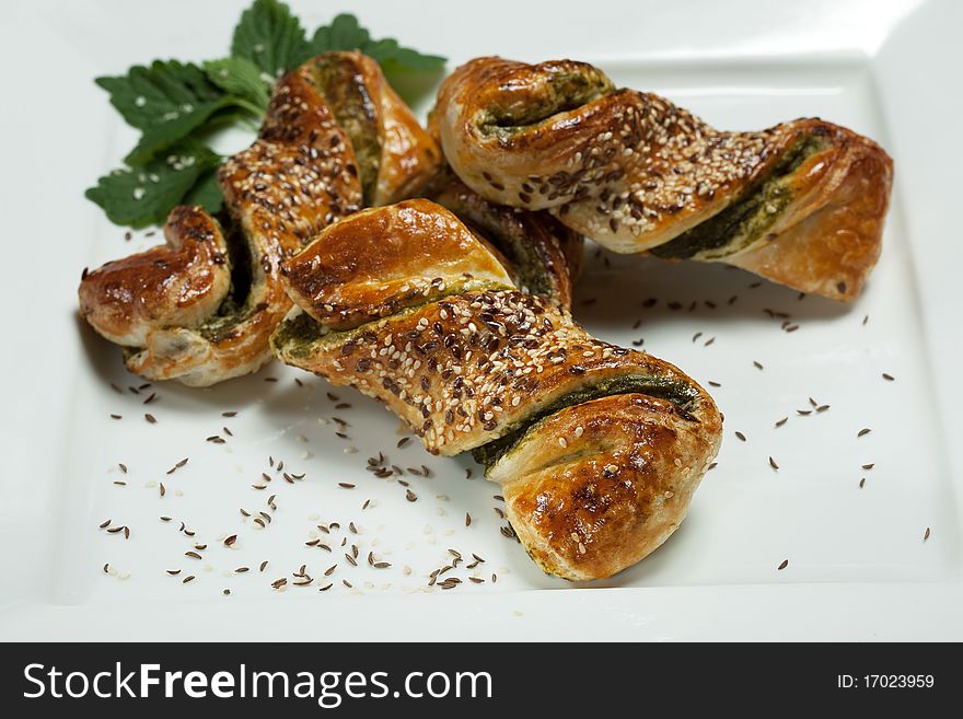 Fresh spinach pastry with sesame seeds and cumin seeds on white plate