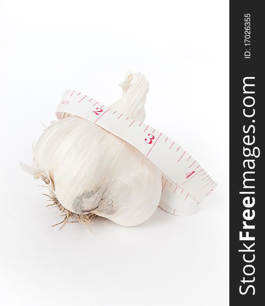 One garlic with a measuring tape around it. Health concept. One garlic with a measuring tape around it. Health concept.