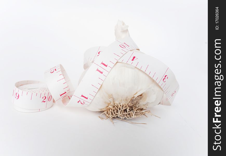 A garlic with a measuring tape around it. Health concept. A garlic with a measuring tape around it. Health concept.