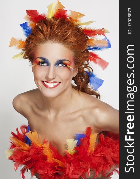 Beautiful woman with face framed in feathers with bright makeup and long faux lashes