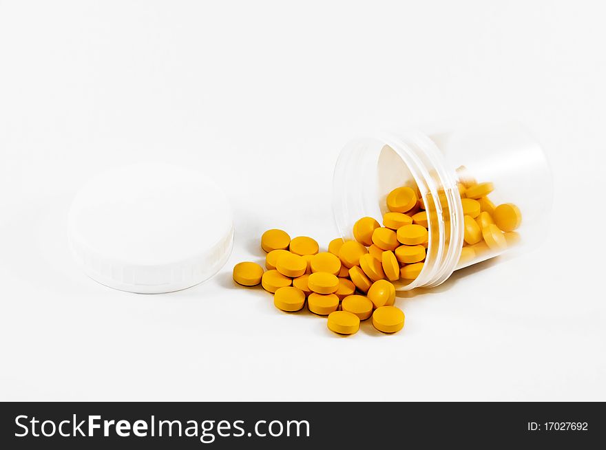 Pot of yellow pills on a light background