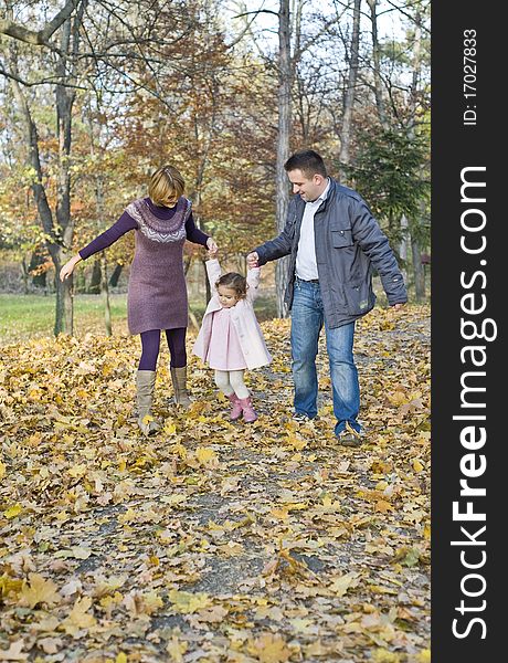 Happy family, mom and dad playing with their little girl in the park in autumn. Happy family, mom and dad playing with their little girl in the park in autumn