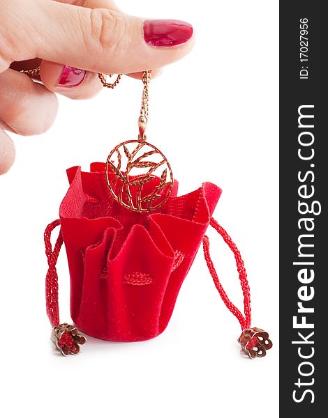 A female hand put golden chain into little red bag isolated over white