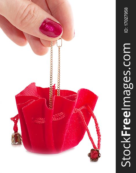 A female hand put golden chain into little red bag isolated over white