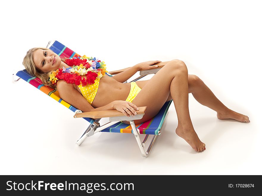 Young woman with yellow bikini and red lei lying in beach chair. Young woman with yellow bikini and red lei lying in beach chair