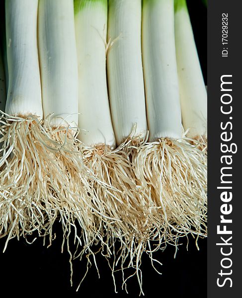 Fresh leeks with roots intact on a market stall