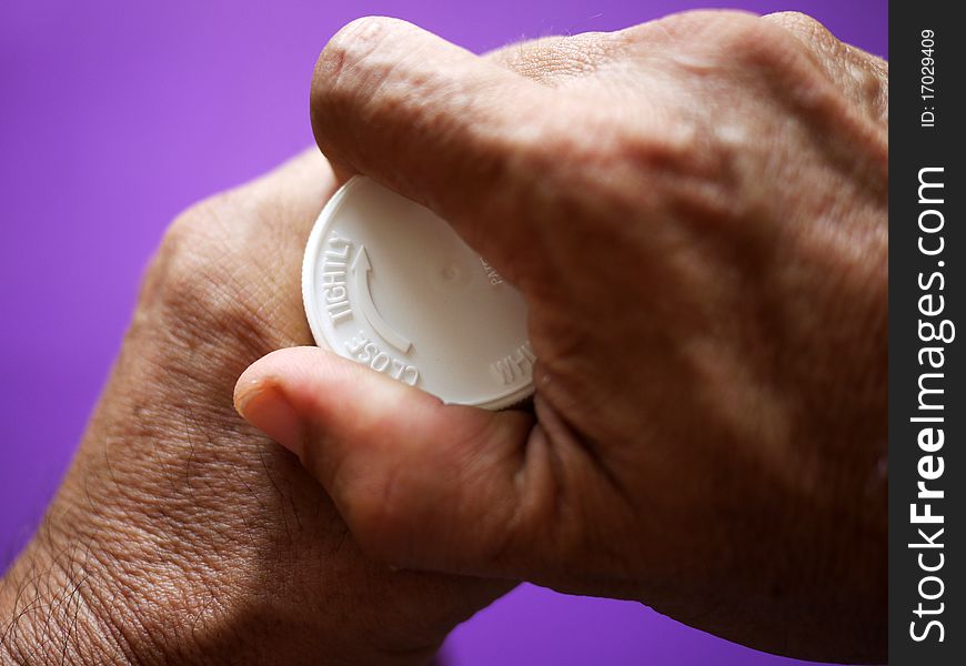 Opening a bottle of pills - lilac background