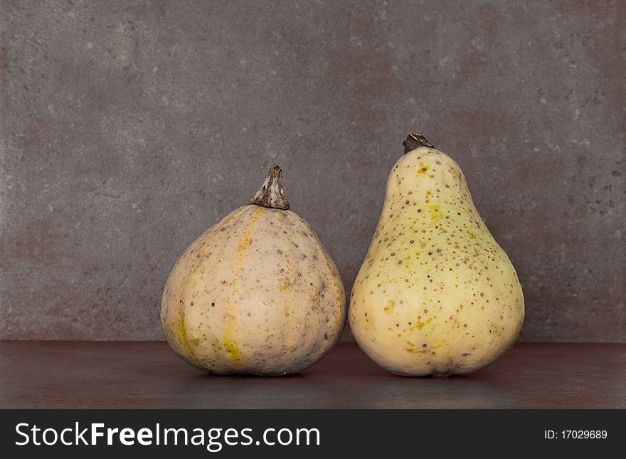 Two squash against a stone tile background