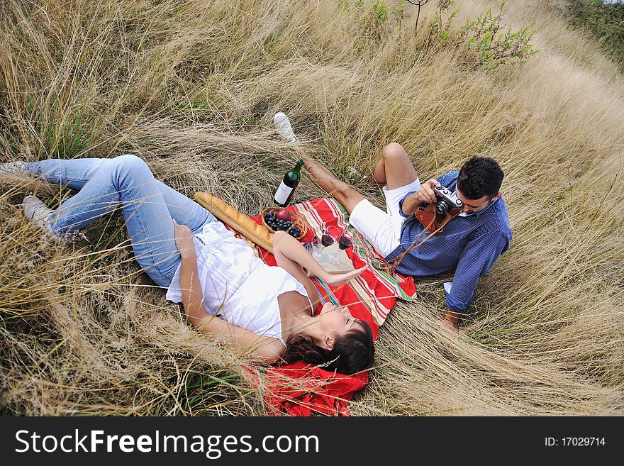 Happy young couple enjoying picnic on the countryside in the field and have good time. Happy young couple enjoying picnic on the countryside in the field and have good time