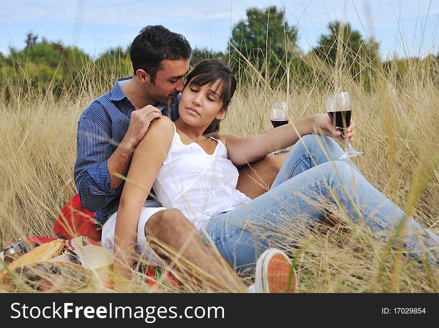 Happy young couple enjoying picnic on the countryside in the field and have good time. Happy young couple enjoying picnic on the countryside in the field and have good time