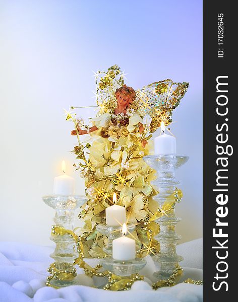 Glimmering golden angle with candles and light blue background. Glimmering golden angle with candles and light blue background