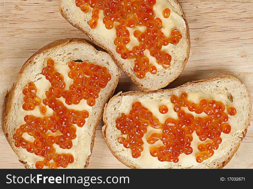 Bread, butter and red caviar on the kitchen board