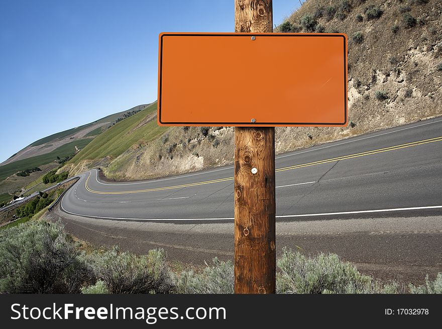 Blank orange construction sign on wooden pole, outdoor day time asphalt highway on background. Blank orange construction sign on wooden pole, outdoor day time asphalt highway on background