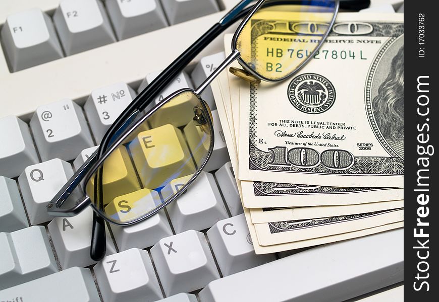 Dollar bills and glasses lying on the keyboard