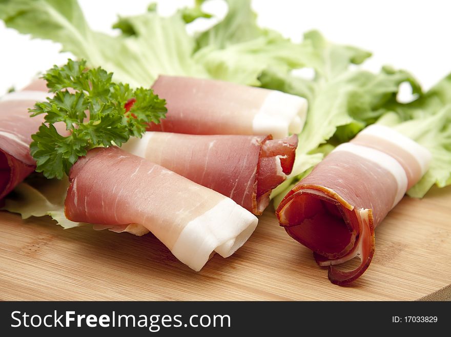 Raw ham and lettuce leaves and parsley onto glass plates