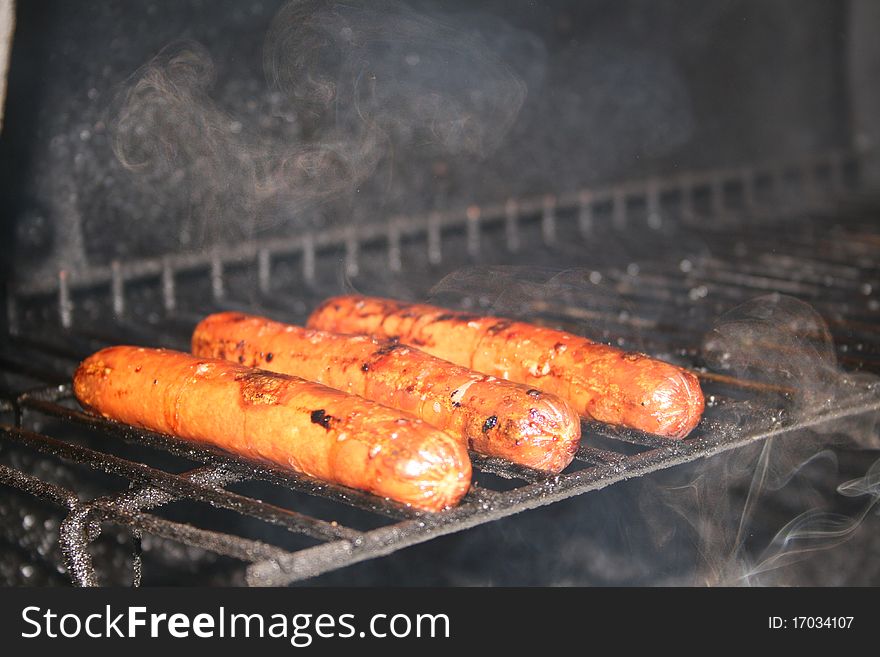 Hotdogs cooking on the grill in the summer time. Hotdogs cooking on the grill in the summer time.