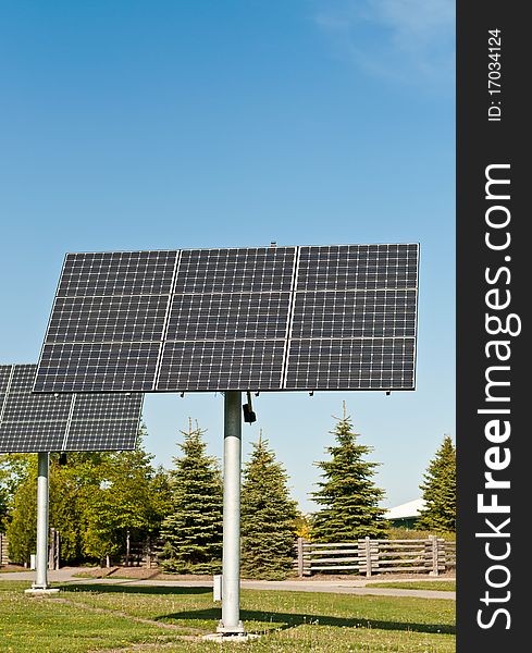 Two arrays of photovoltaic solar panels stand in the grass in a public park. Two arrays of photovoltaic solar panels stand in the grass in a public park.