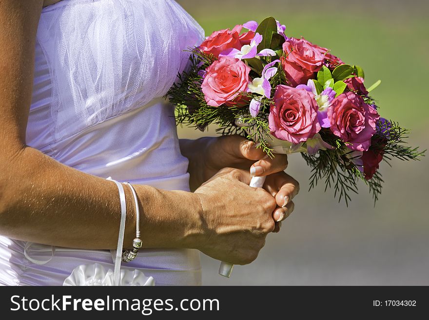 A closeup shot of a bride holding a beautiful bouquet of red and pink flowers on her wedding day. A closeup shot of a bride holding a beautiful bouquet of red and pink flowers on her wedding day