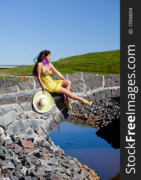 Happy Beautiful Girl Sitting On stone bridge in yellow dress