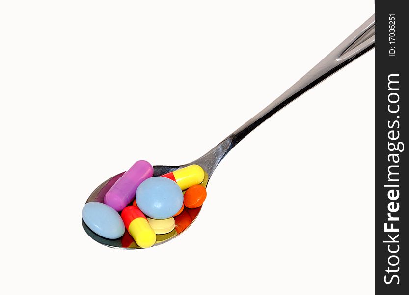 Multi-colored tablets in a steel spoon. Multi-colored tablets in a steel spoon