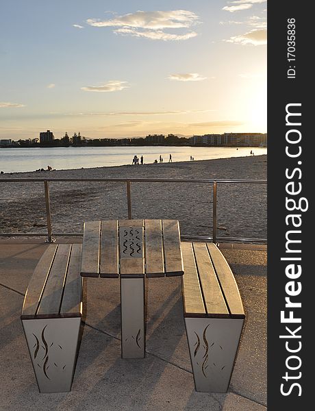 Sun setting at the beach with bench and table int he foreground. Sun setting at the beach with bench and table int he foreground