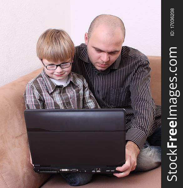 Father son sitting on the couch with a computer