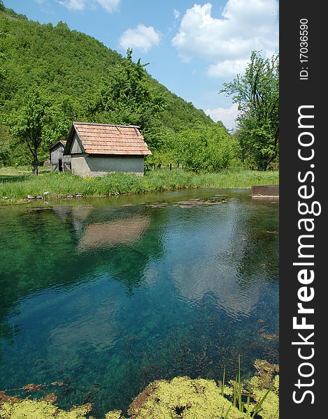 View of a lake house in Iada valley, with water in the foreground and trees in the background. Transylvania, Romania. View of a lake house in Iada valley, with water in the foreground and trees in the background. Transylvania, Romania