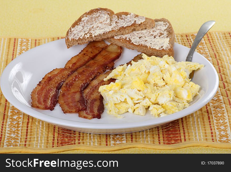Bacon and scrambled egg breakfast with buttered toast. Bacon and scrambled egg breakfast with buttered toast