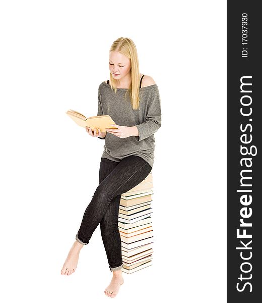 Young girl sitting on a pile of books reading isolated on white background. Young girl sitting on a pile of books reading isolated on white background