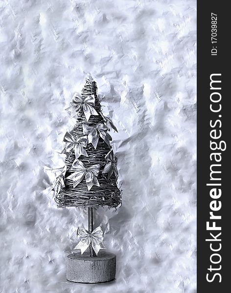 Silver christmas tree with decorative bows on the abstract background