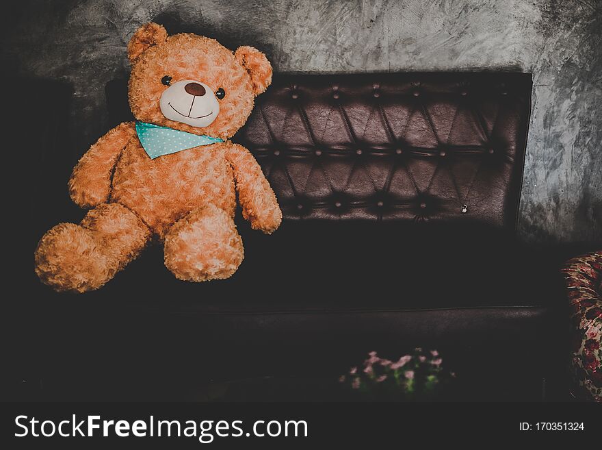 Inside modern coffee shop decoration.Teddy Bear on Brown Leather Couch