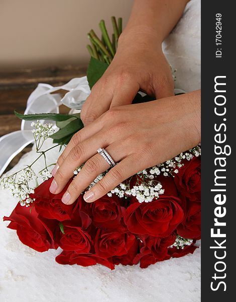 Bride resting her hand on a red rose bridal bouquet. Bride resting her hand on a red rose bridal bouquet