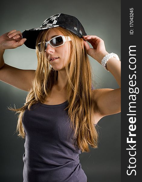 Portrait of a woman with sunglasses and basecap in the studio