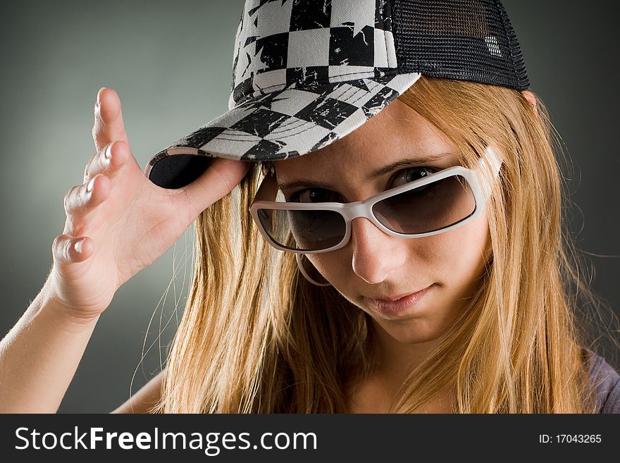 Portrait of a woman with sunglasses and basecap in the studio