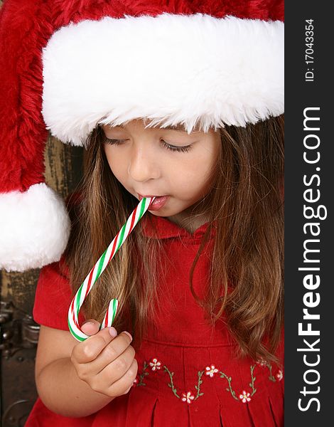 Beautiful brunette christmas girl eating a candy cane