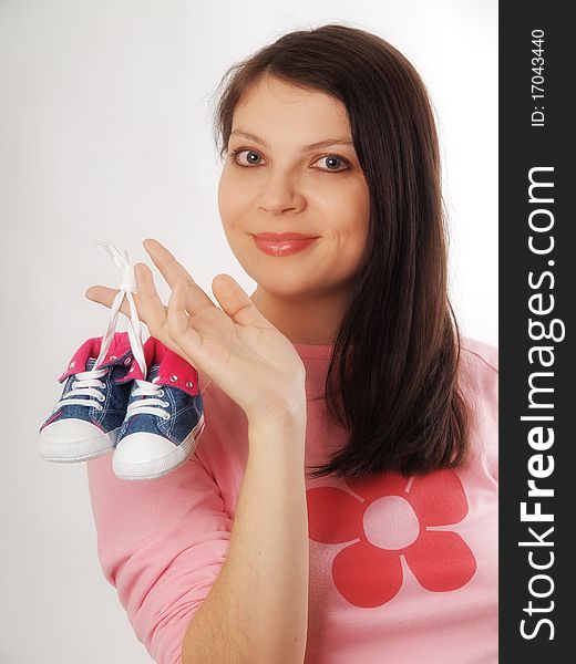 Pregnant woman holding shoes in studio. Pregnant woman holding shoes in studio