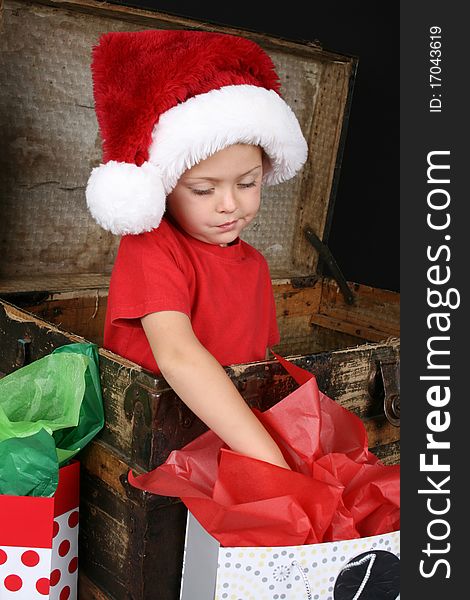 Little boy wearing a christmas hat looking inside the giftbag. Little boy wearing a christmas hat looking inside the giftbag