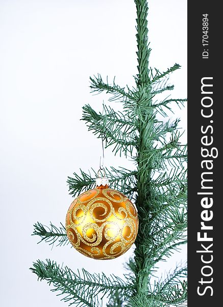 Golden ball on fir-tree on white background