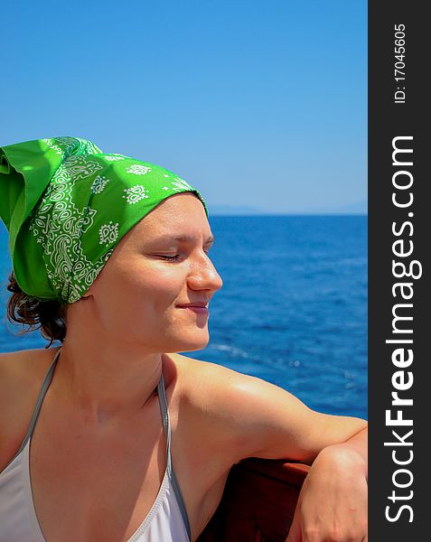 Young woman in soft focus relaxing near the sea, with eyes close and a green bandana. Young woman in soft focus relaxing near the sea, with eyes close and a green bandana