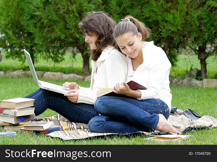 Two student girls with books and laptop on natural background. Two student girls with books and laptop on natural background