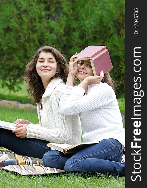 Two student girls with books and laptop on natural background. Two student girls with books and laptop on natural background