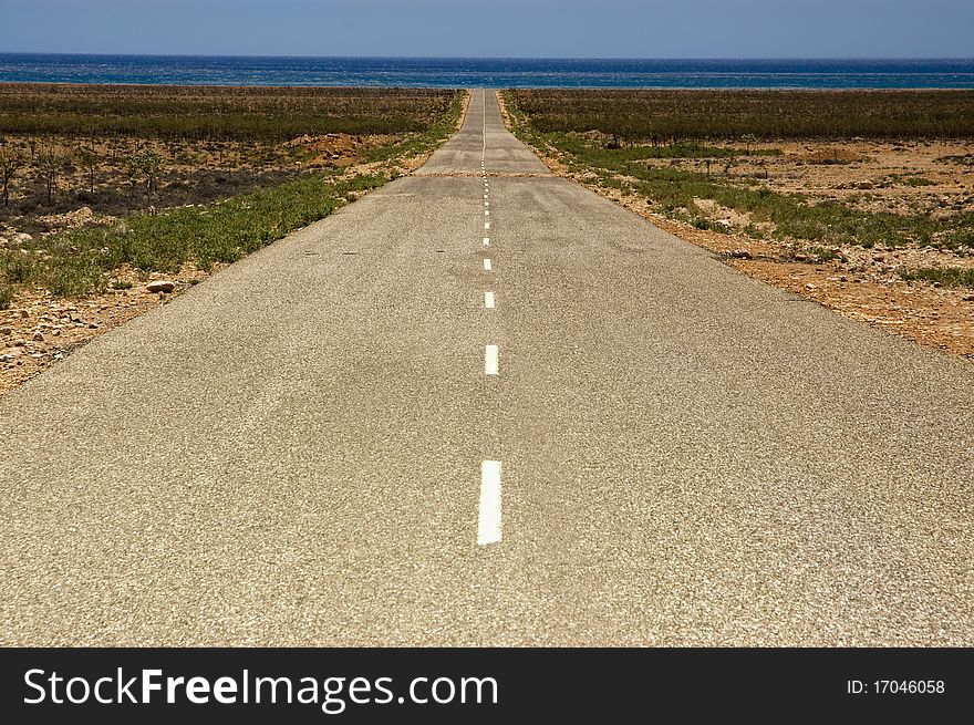 Straight road going through farmland in rural Socotra, Yemen.