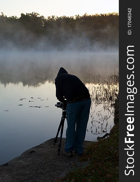 Professional photographer filming moving fog across early morning lake. Professional photographer filming moving fog across early morning lake