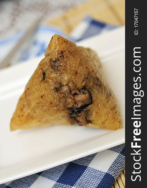 Unwrapped dumpling on white plate showing glutinous rice texture.